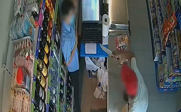 El momento en el que el atracador amenazaba al empleado de la tienda.