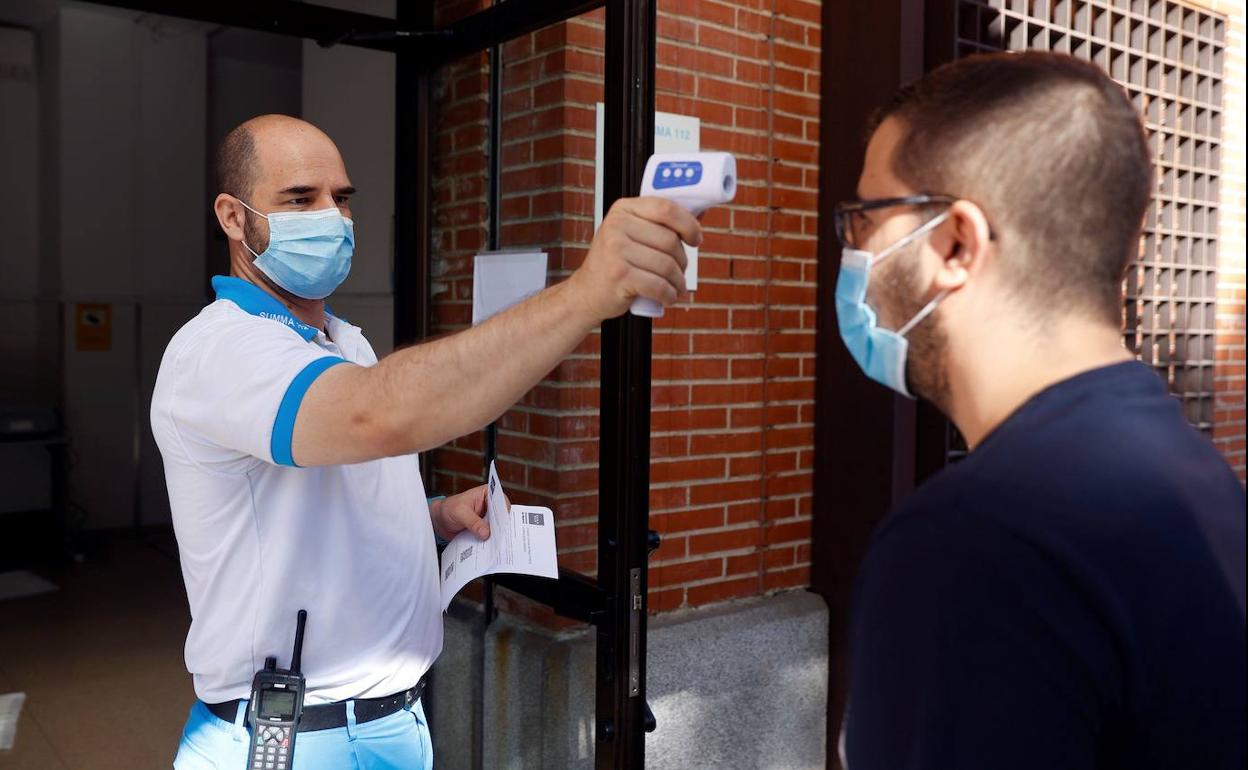 Un sanitario toma la temperatura a un hombre en un ambulatorio. 