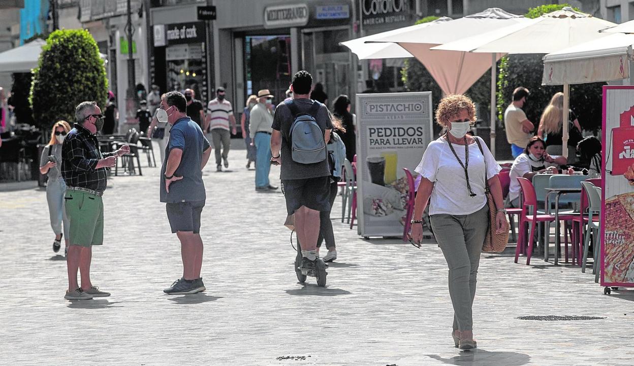 Un joven circula en patinete entre numerosos viandantes, por la calle Puerta de Murcia. 