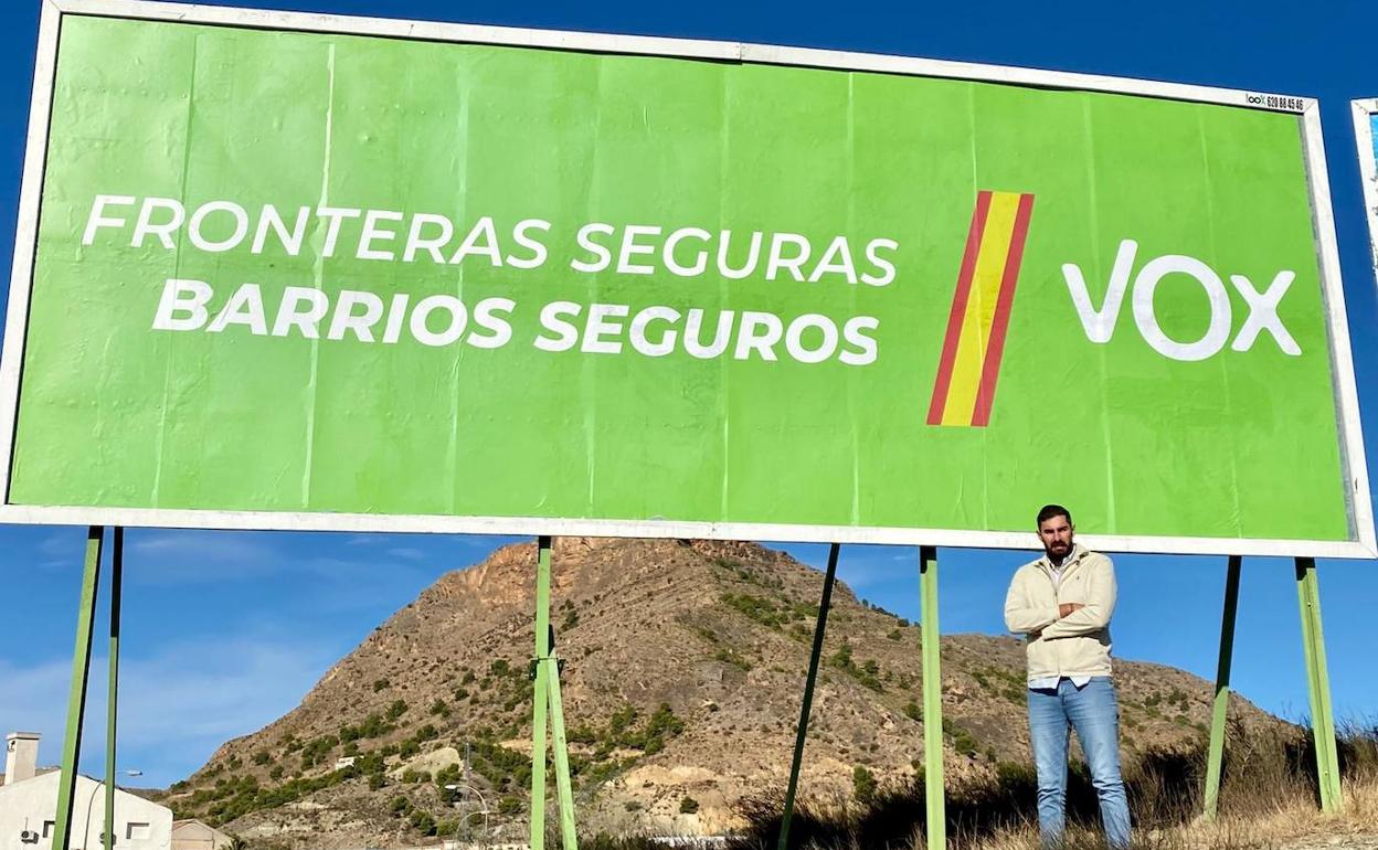 El presidente de Vox Murcia, José Ángel Antelo, al lado de una de las vallas. 