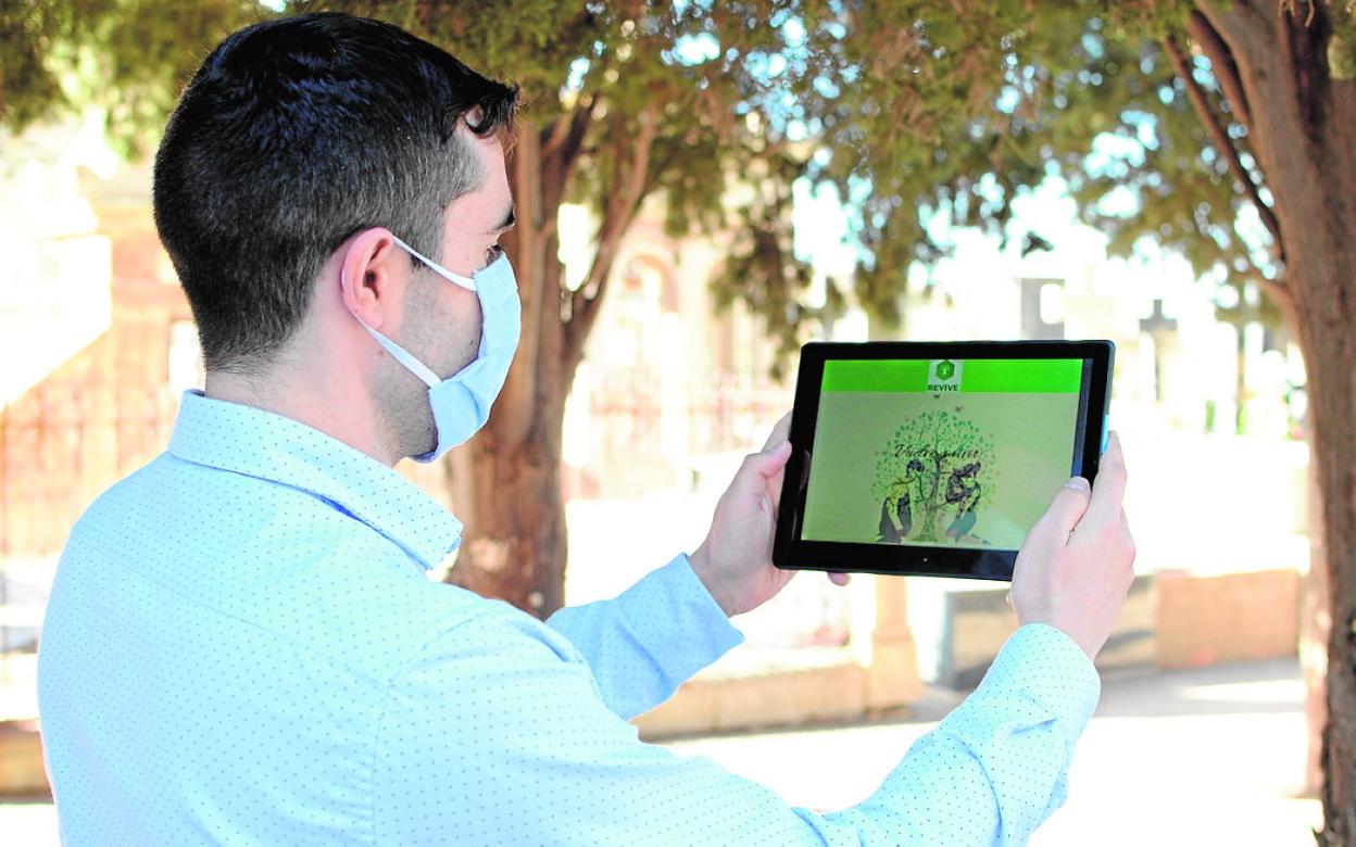 Andrés Martínez, con una tableta en la que se ve la red social Revive, en el cementerio de Los Remedios. 