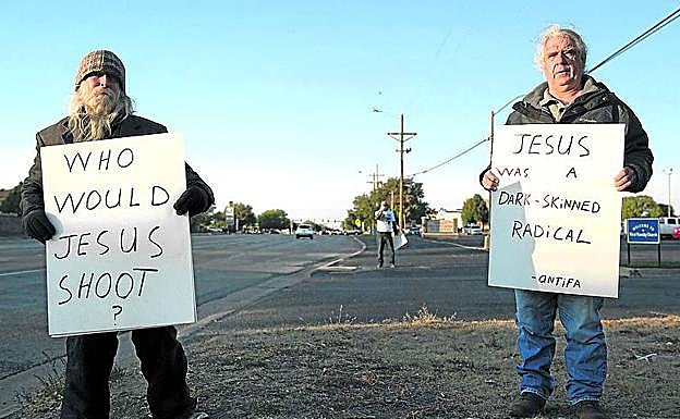 Críticos. Rusty Donaldson (con barba) y Charles Kempf enseñan los carteles con los que acuden a los actos republicanos. 