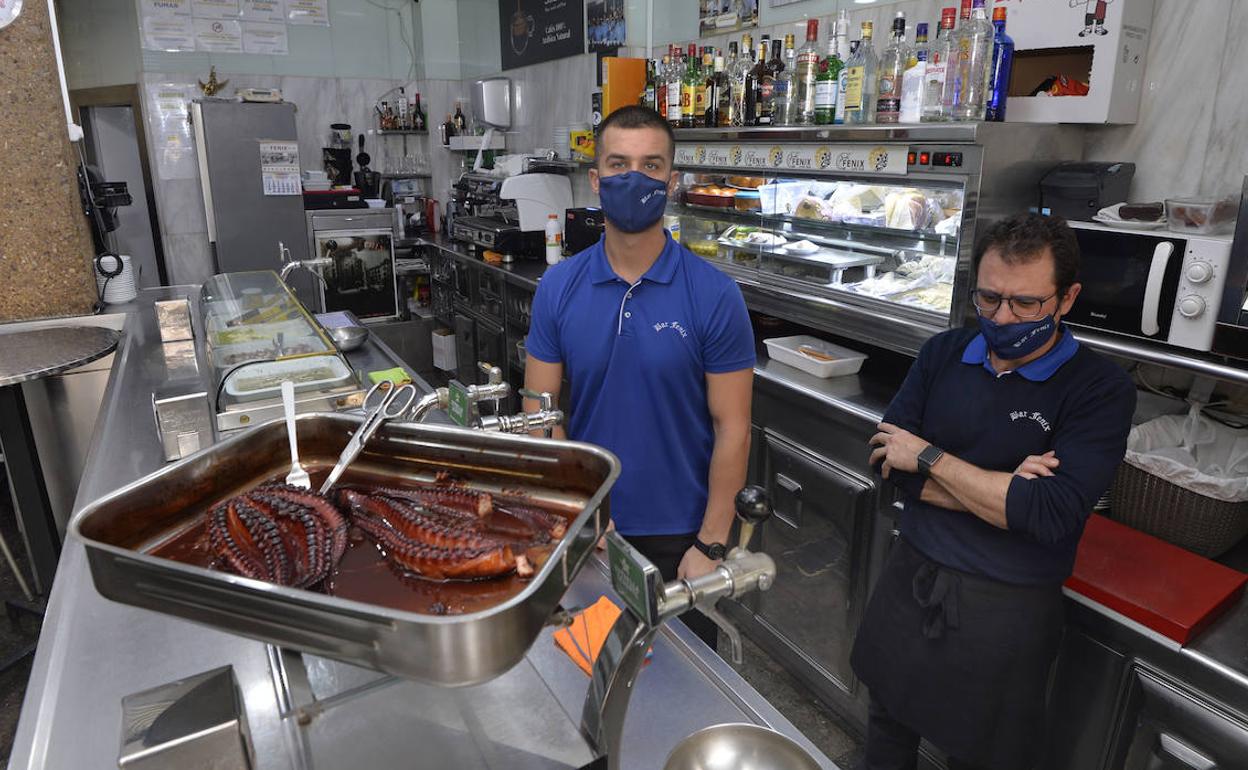 Daniel Navarro (dcha.), propietario del bar Fénix de la Plaza de Las Flores de Murcia, junto a uno de sus empleados, tras conocer la orden de cierre este miércoles.