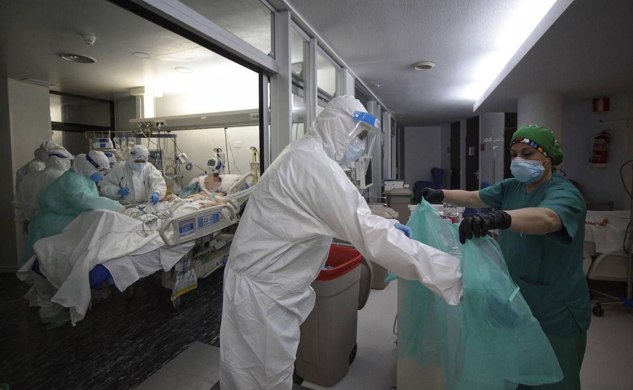 Un sanitario se protege para visitar a un enfermo en el hospital Morales Meseguer.