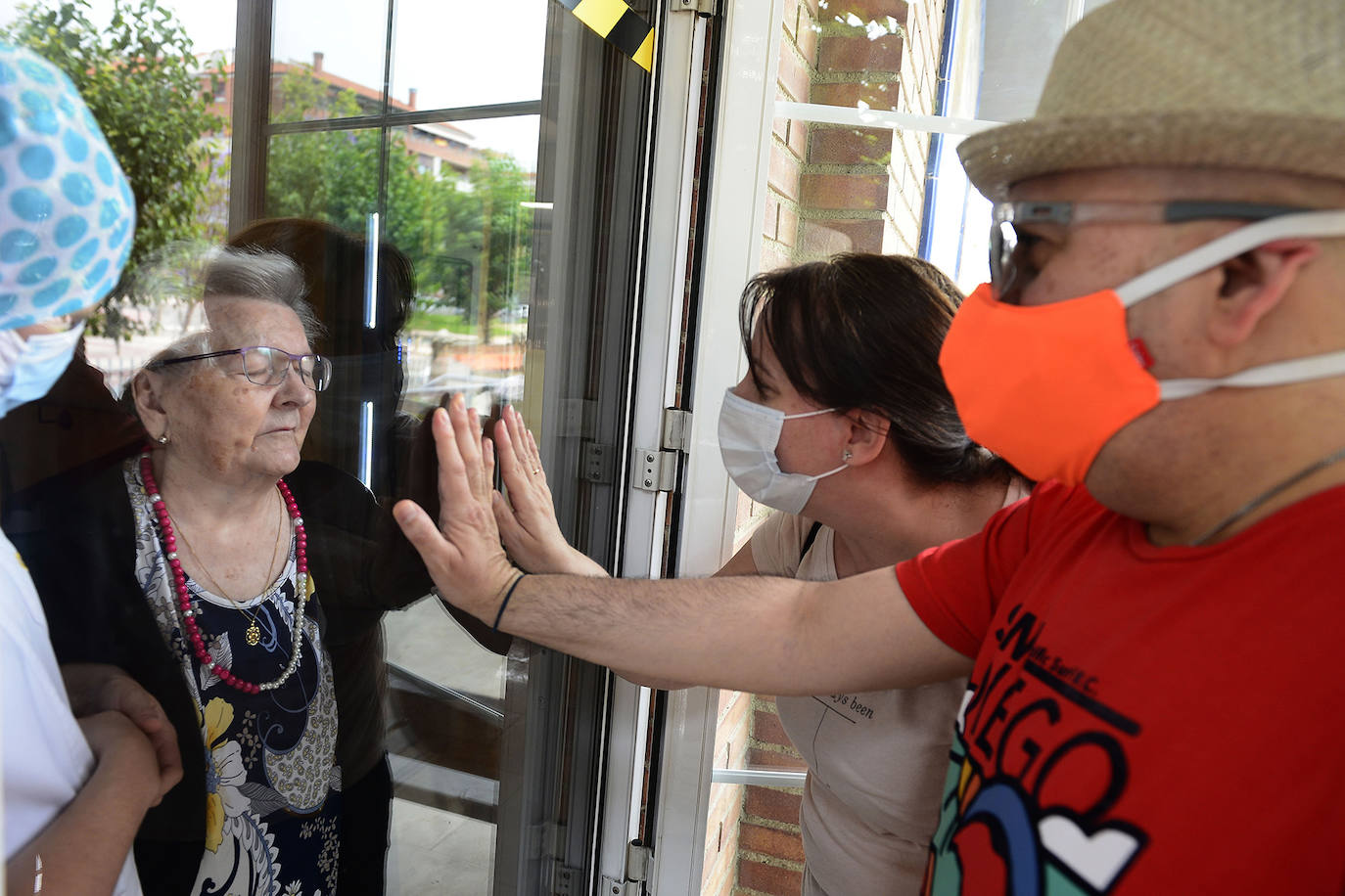 26-05-2020. Los cerca de 5.000 mayores ingresados en residencias de la Región de Murcia empiezan a recibir las visitas de sus familiares después de tres meses de aislamiento. Sin contacto físico, pero con mucha emoción por el reencuentro, los ancianos reciben el calor de los suyos. En la foto, una anciana en la residencia Virgen de la Fuensanta se encuentra con su familia.