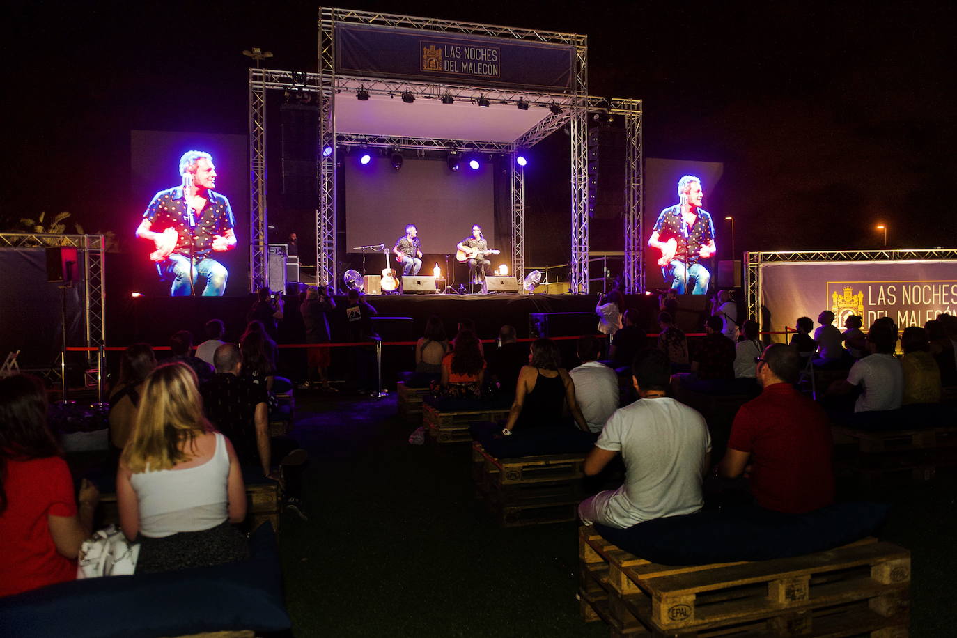 08-07-2020. Las Noches del Malecón arrancan en los jardines de Murcia Río con Carlos Tarque y Ricardo Ruipérez, componentes de M Clan, en su vuelta a los escenarios tras un tiempo lanzando sus carreras en solitario. El nuevo ciclo se realiza con un aforo muy reducido, siguiendo las medidas de seguridad establecidas para la celebración de espectáculos al aire libre, con el público distribuido respetando la distancia reglamentaria, y en sillas alrededor de mesas decorativas realizadas con palés de madera.