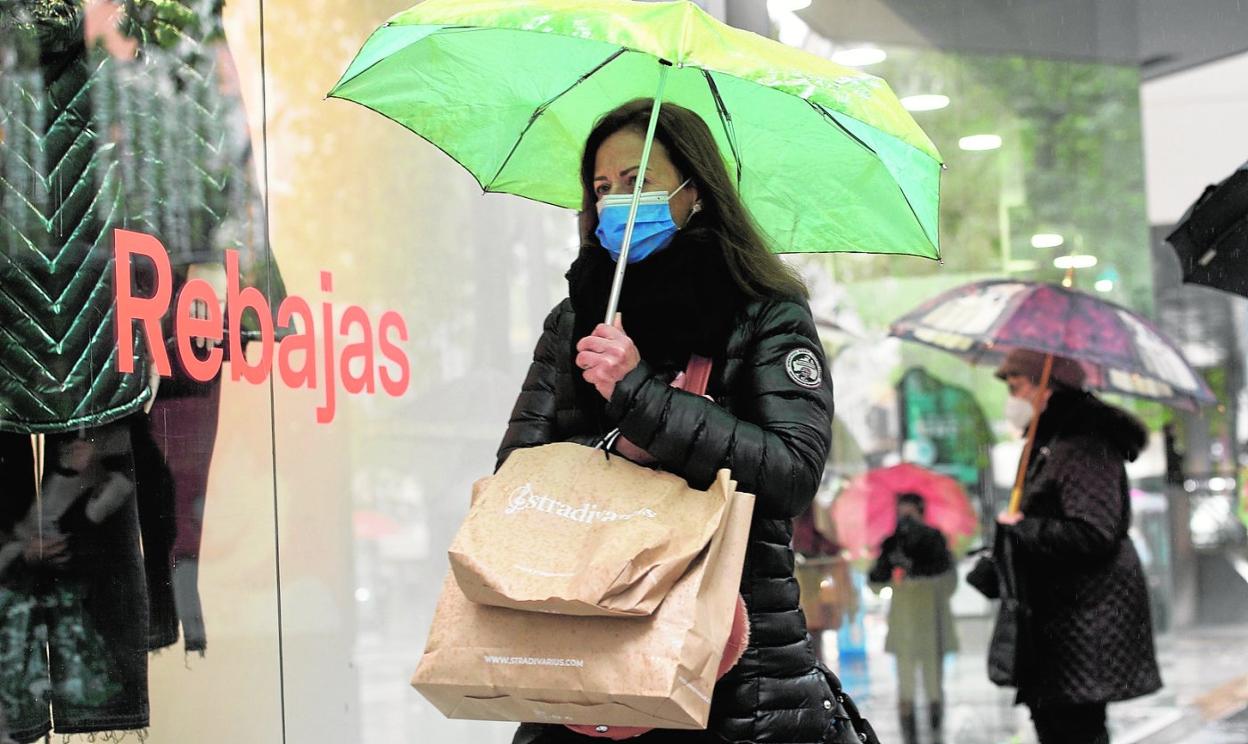 Una clienta pasa frente a un escaparate en Murcia tras realizar varias compras durante el primer día oficial de la campaña de rebajas. 