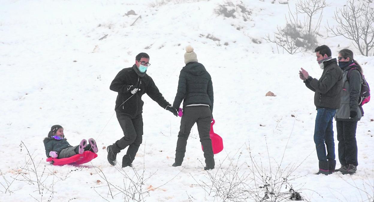 Un grupo de vecinos disfrutan de la nieve, con un trineo, y toman fotografías en la zona de Venta de Cavila. 