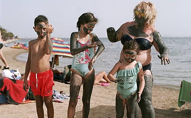 Una familia cubierta de lodo en la playa de Lo Pagán.