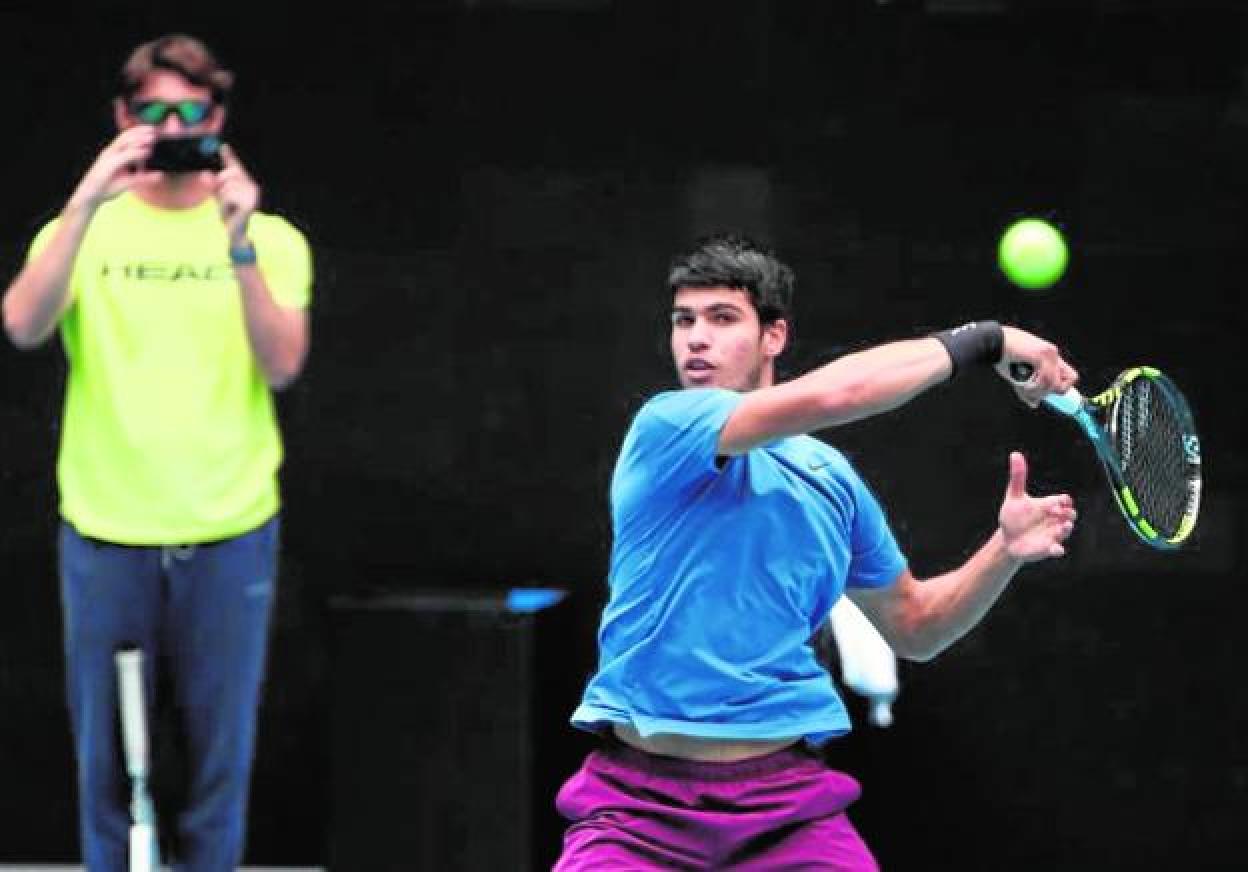 Carlos Alcaraz peloteando ayer con Rafa Nadal en el Melbourne Park, con Juan Carlos Ferrero detrás de él grabando el entrenamiento. 