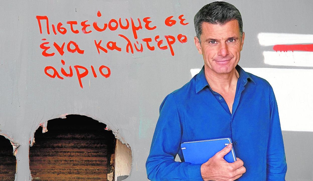 El escritor Pedro Olalla, delante de un eslogan en griego que dice «creemos en un mañana mejor». 