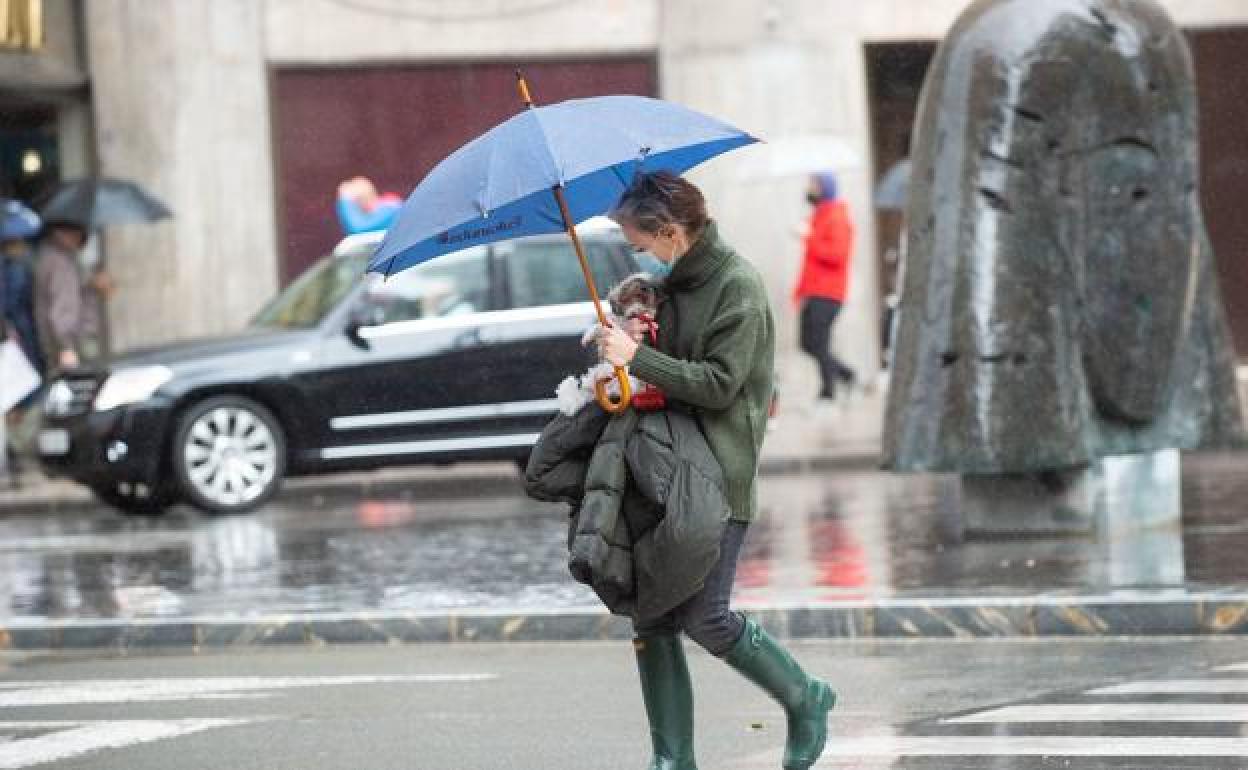 Una mujer se protege de la lluvia en Murcia, en una imagen de archivo.