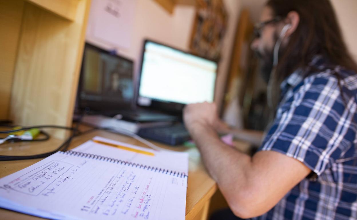 Una persona teletrabajando desde casa con un portátil, en una imagen de archivo.
