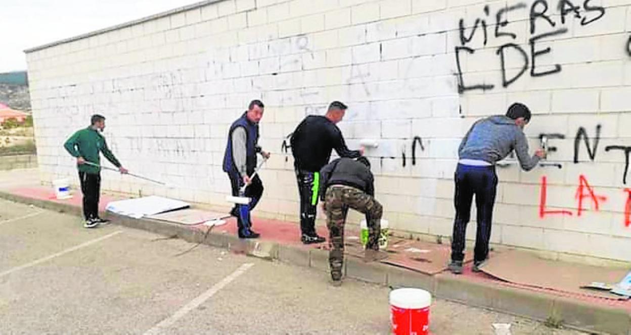 Varios vecinos eliminan las pintadas contra el alcalde, ayer. 