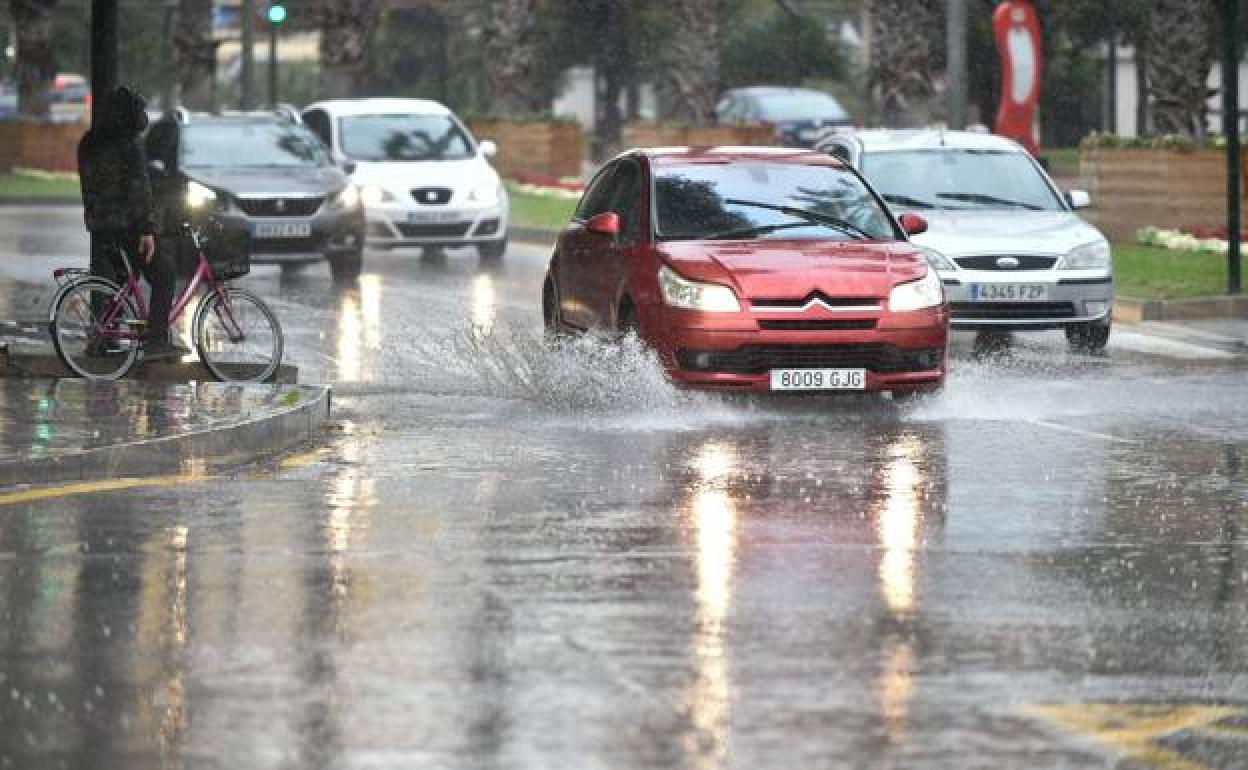 Varios coches circualando con mucha agua en la calzada, en una imagen de archivo.