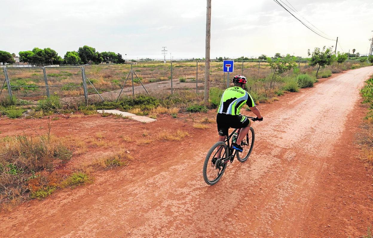 Un ciclista pasa junto a los terrenos donde será construido el colegio de La Aljorra. 