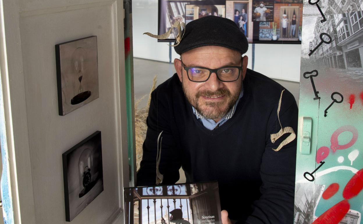 Pablo Sánchez del Valle con un ejemplar del libro 'Sonrisas confinadas', en una de las ventanas expuestas en la muestra. 