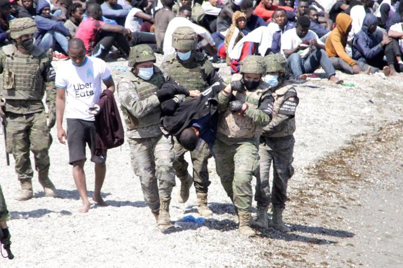 Un grupo de soldados conduce a dos inmigrantes hacia la puerta que los devolverá a Marruecos.