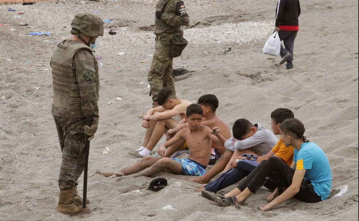 Miembros del Ejército de Tierra vigilan a un grupo de inmigrantes menores que cruzaron este martes uno de los espigones fronterizos de Ceuta 