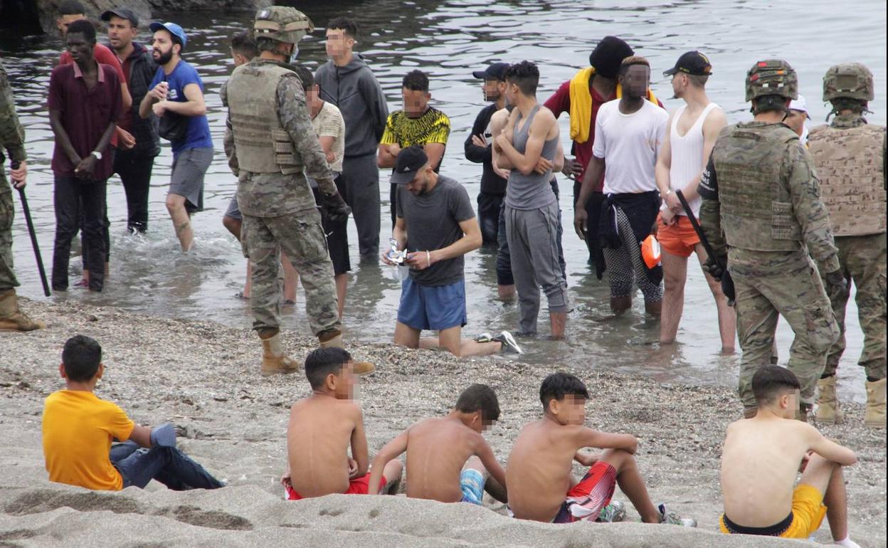 Miembros del Ejército de Tierra vigilan a un grupo de inmigrantes que lograron cruzar uno de los espigones fronterizos de Ceuta.