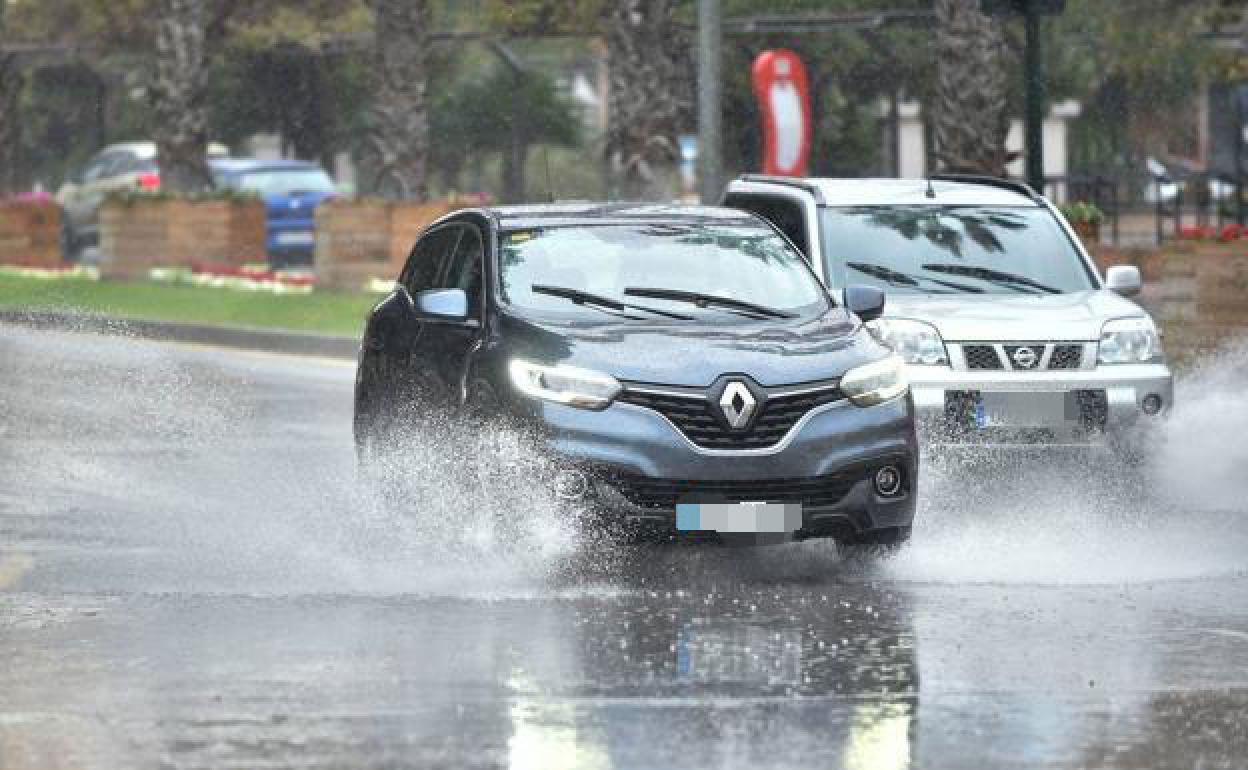 Dos vehículos pasando por calles encharcadas por la lluvia, en una imagen de archivo.