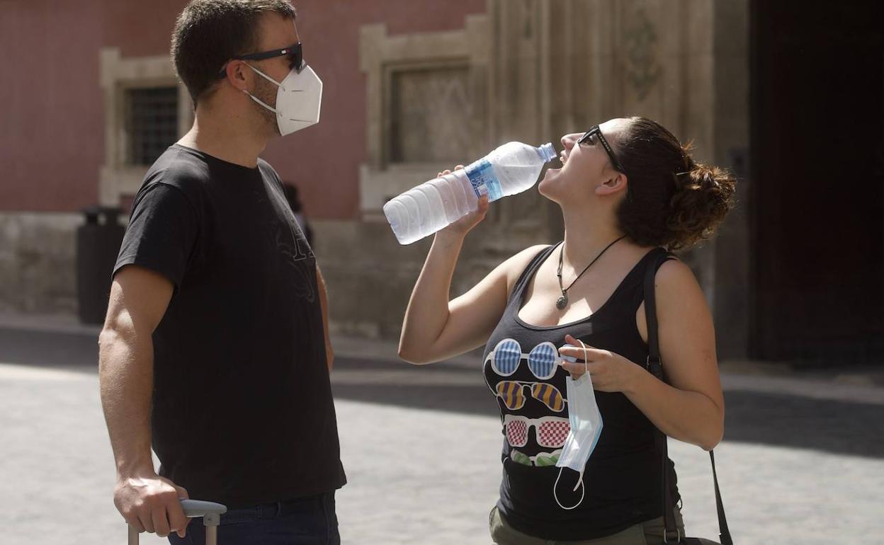 Una chica bebiendo agua en un día caluroso en Murcia, en una imagen de archivo.