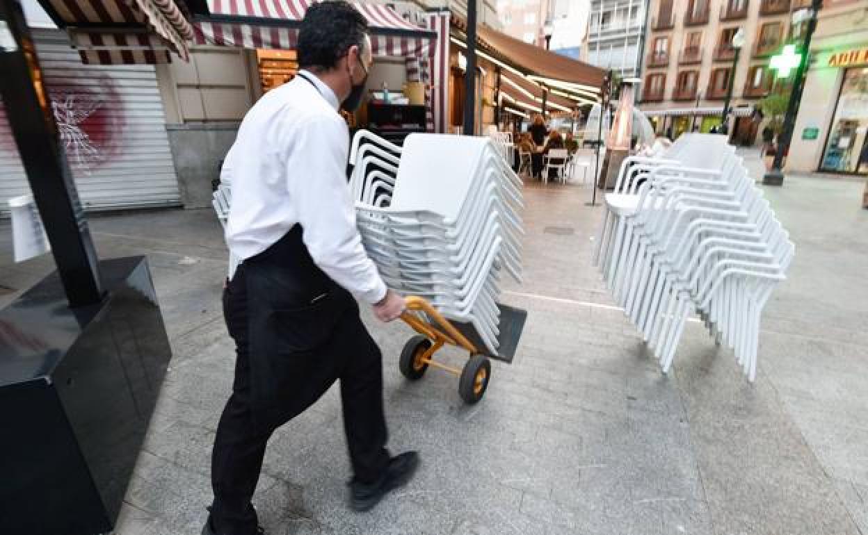 Un camarero recoge las sillas de una terraza, en una imagen de archivo. 