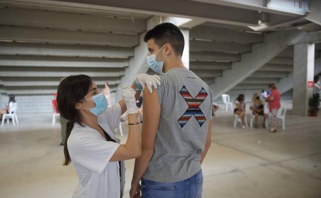 Galería. Una sanitaria pone la vacuna contra la Covid-19 a un joven en el estadio Enrique Roca de Murcia, este lunes.