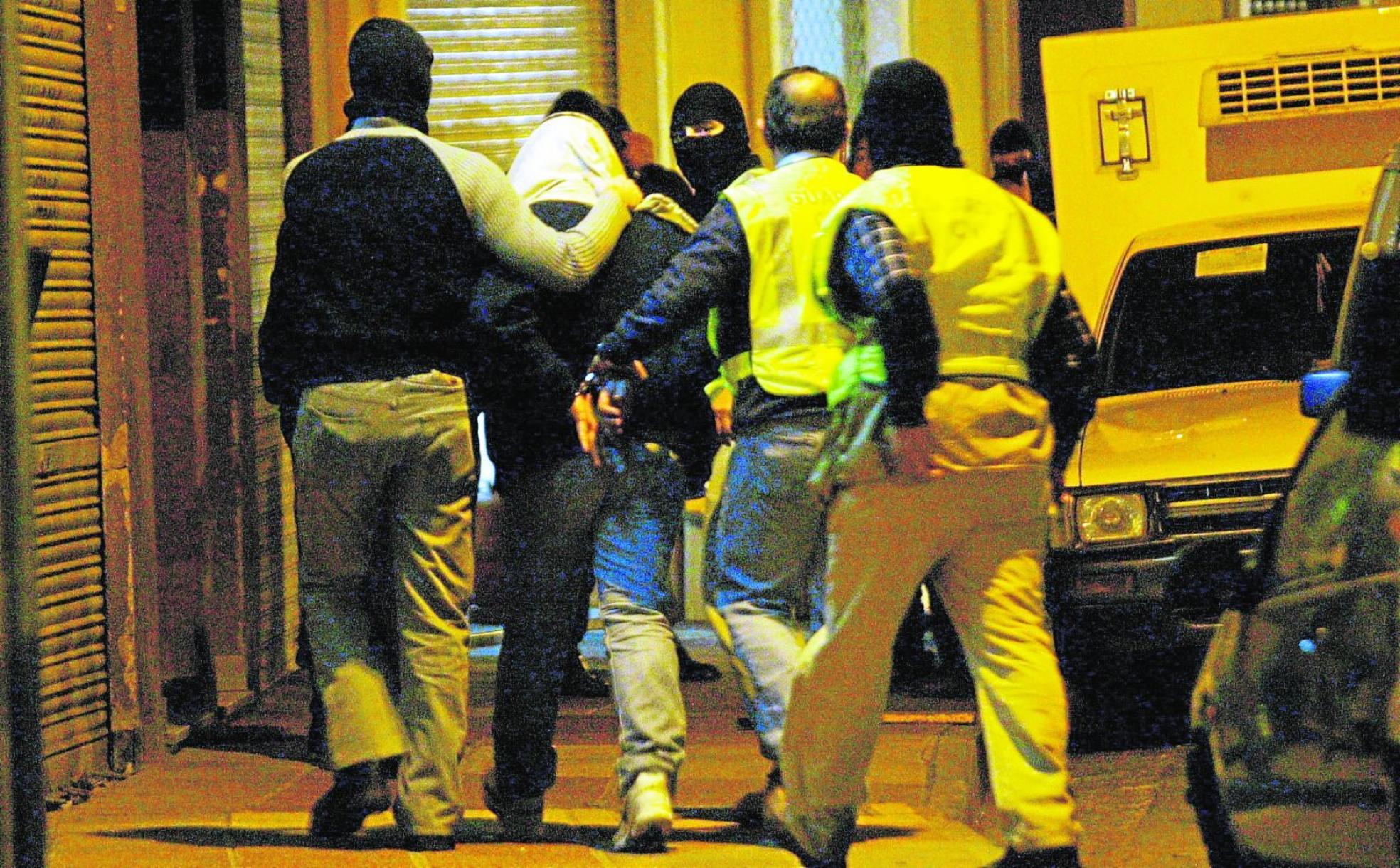Guardias civiles encapuchados conducen al sospechoso de haber proporcionado los pasaportes del 11-S tras su detención en un locutorio del barrio del Carmen en Murcia, en 2004. 