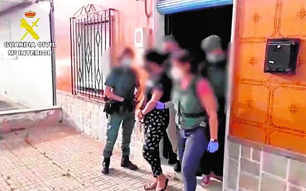 Una guardia civil traslada a una de las dos detenidas, en su vivienda de Torre Pacheco. 