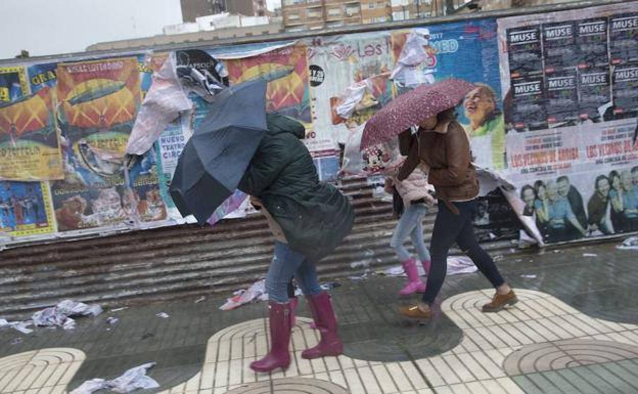 Varias personas se protegen de la lluvia y el viento.