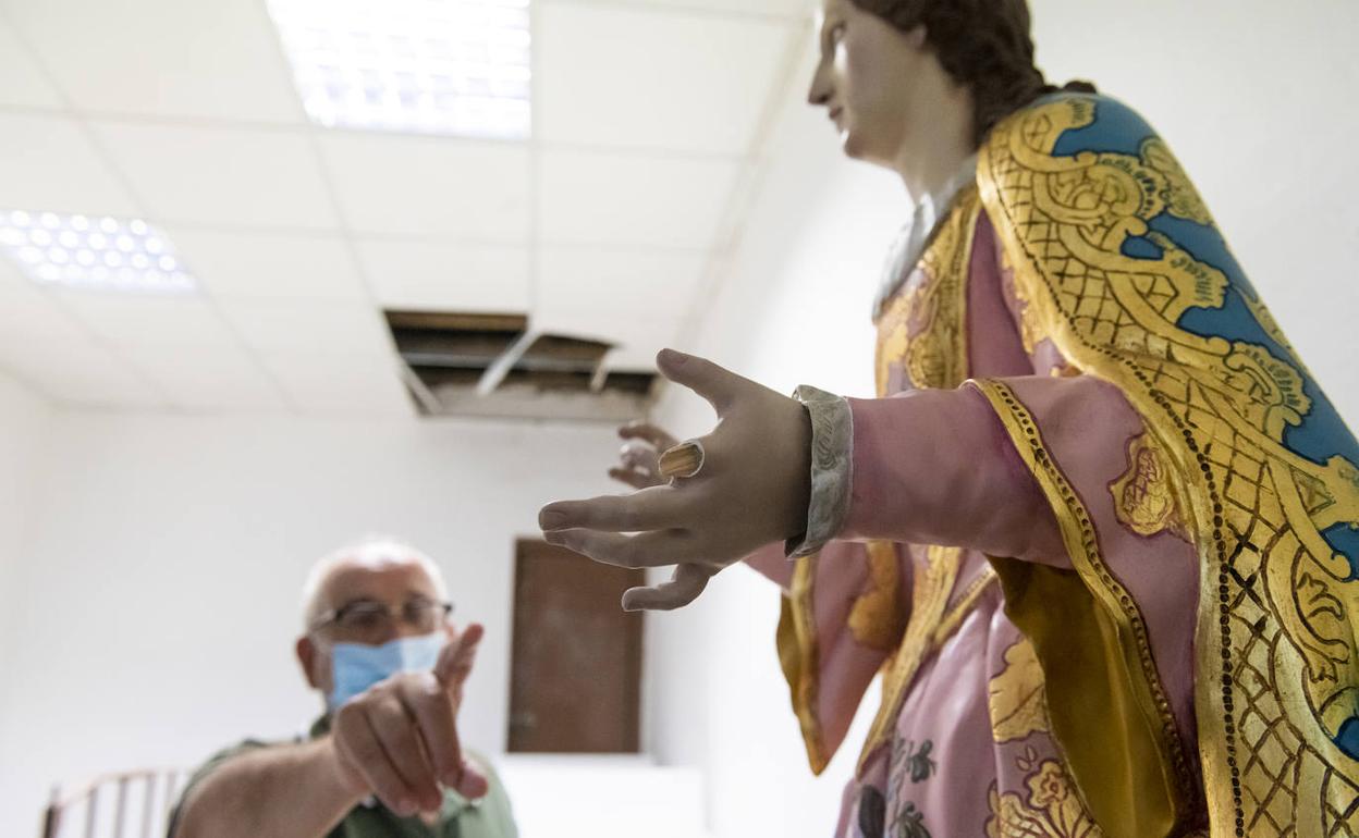 El párroco señala el dedo roto a una imagen de la Virgen.