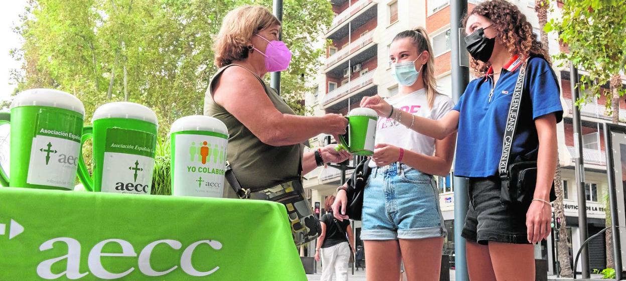 Dos jóvenes realizan un donativo en una de las mesas petitorias instaladas en la avenida Alfonso X de Murcia. 