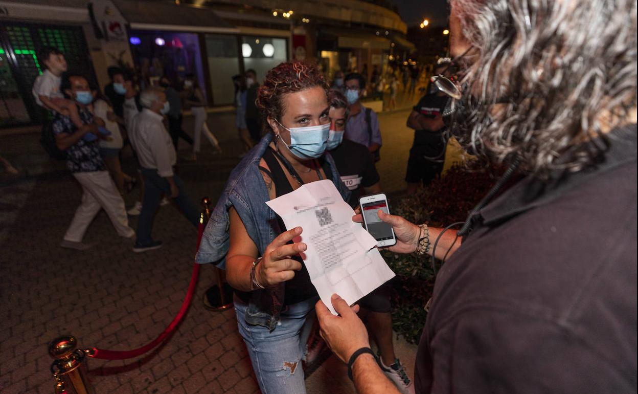 Una mujer presenta el pasaporte Covid para entrar a un local en Galicia.