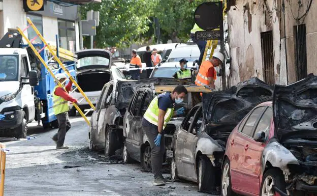 Un agente de la Policía Nacional inspecciona, ayer, uno de los coches incendiados en la Gran Vía de Molina de Segura. 