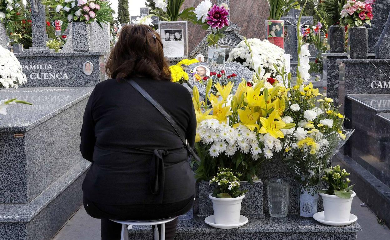 Una mujer visita la tumba de un familiar fallecido.