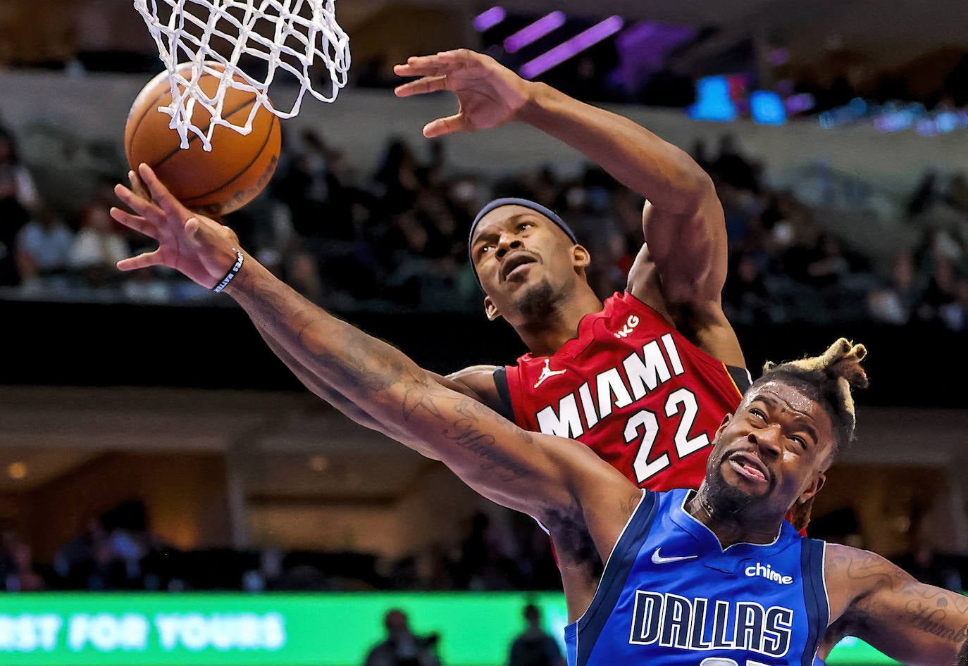 El delantero del Miami, Heat Jimmy Butlerr, dispara sobre el delantero de los Dallas Mavericks, Reggie Bullock.