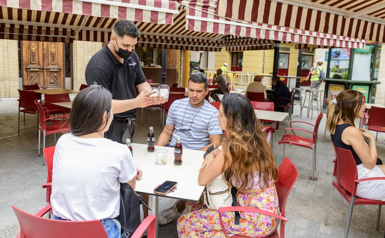 Un camarero atendiendo a unos clientes en la terraza de un bar.