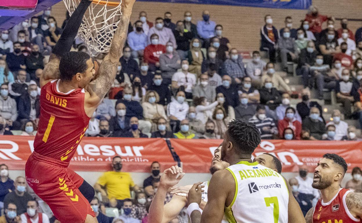Davis se cuelga de la canasta tras anotar ante la mirada de los rivales y compañeros.