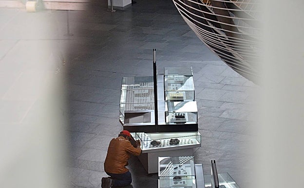 Un hombre fotografía algunas de las monedas que quedaron expuestas. 