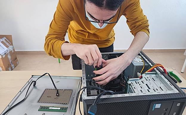 Un alumno del programa repara un ordenador.