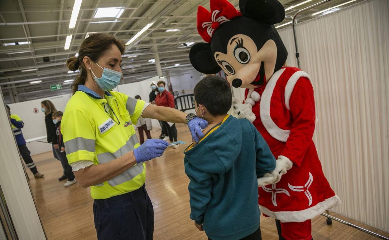 Una enfermera pincha a un niño, acompañado por un personaje de Disney, en el centro comercial La Rambla. 