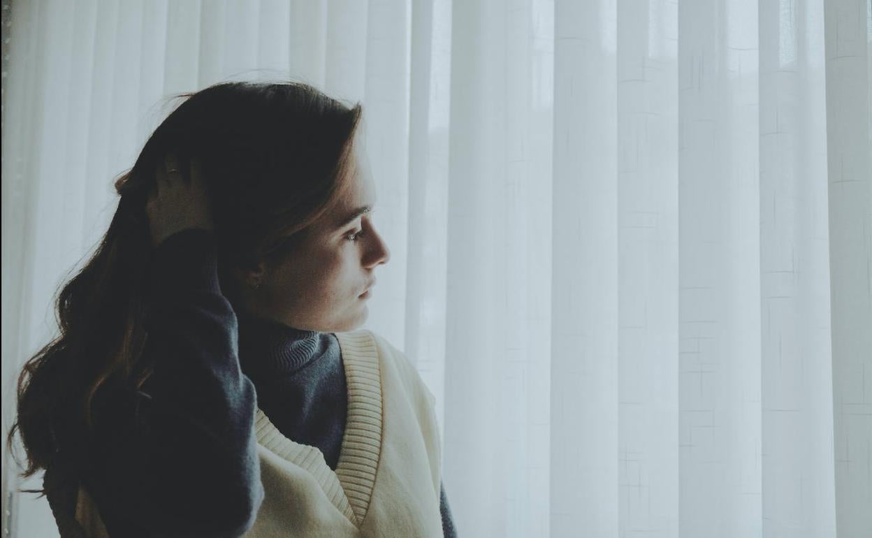 Una mujer mira por la ventana.