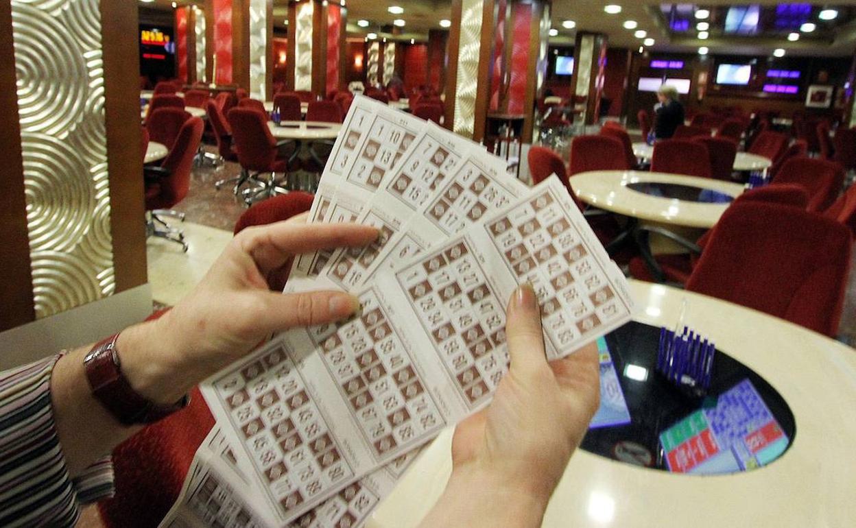 Una persona con varios cartones de bingo en un casino.