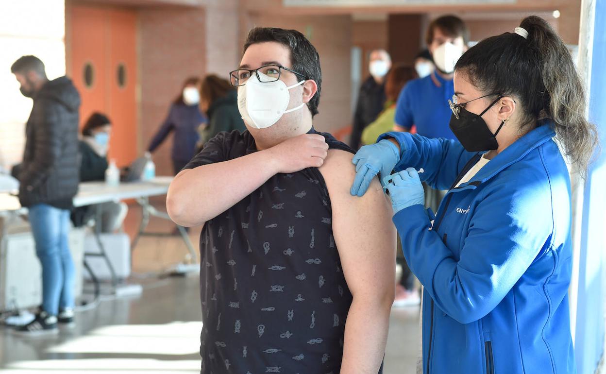 Una sanitaria vacuna a un joven, en una imagen de archivo.