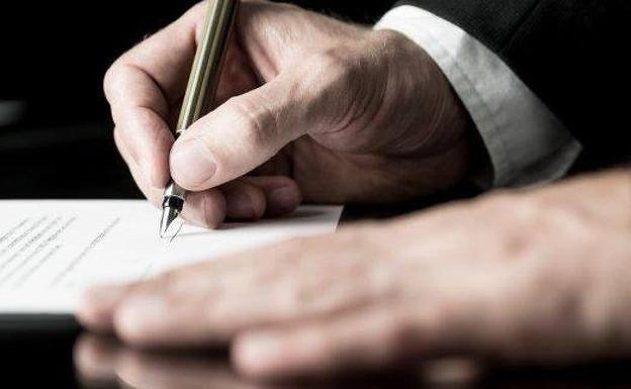 Una persona firma ante notario.
