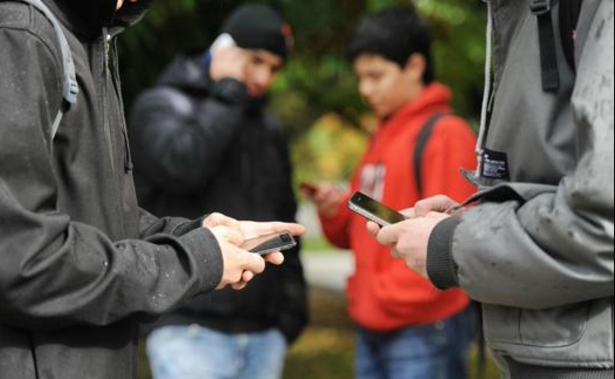 Adolescentes utilizan sus teléfonos móviles. 