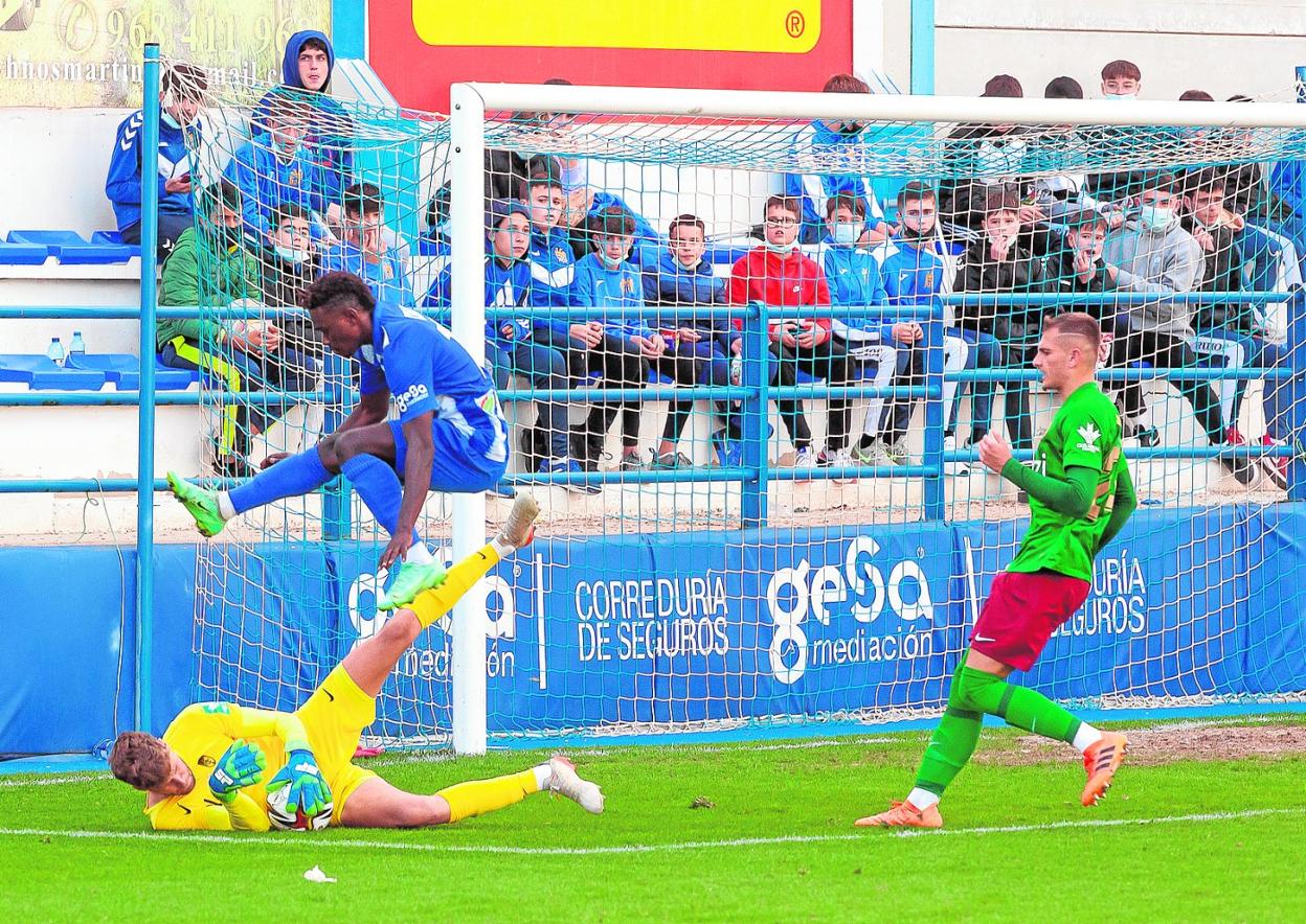 El jugador del Águilas Cellou salta sobre Ángel, portero del Recreativo Granada. 