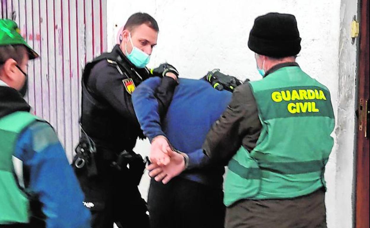 Un policía nacional y un guardia civil arrestan a uno de los sospechosos.