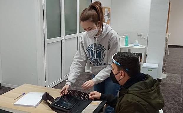 Una de las ayudantes personales enseña a un usuario de Ápices a manejar una tablet. 